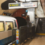 A Bakerloo Line train rests at Charing Cross Underground Station, beneath the heart of central London. Once a junction for both the Bakerloo and Jubilee lines, Charing Cross now functions as the southern terminus for Bakerloo services, connecting to the mainline station above. The photograph highlights the tunnel portal with its characteristic red tiles and the clean signage pointing toward the Northern line and the National Rail concourse. Opened in 1906 and expanded through the 1970s, the station remains an emblem of the Underground’s architectural layering—where Edwardian infrastructure meets modern transit demands.