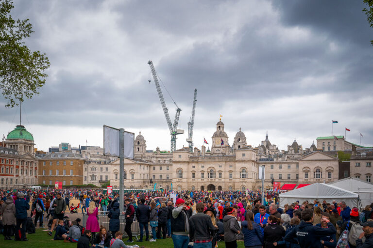 London Marathon Finishers 2019 2 Participants and supporters gather at Horse Guards Parade near the finish area of the 2019 London Marathon. The scene captures the mix of exhaustion and celebration as runners cross the line against a backdrop of historic architecture and temporary infrastructure erected for the event. Cranes tower above the domes and facades of Whitehall’s government buildings, underscoring the juxtaposition of London’s centuries-old civic landmarks and its ever-changing skyline. The annual marathon, one of the world’s largest, draws tens of thousands of athletes and spectators to central London, filling the ceremonial grounds with color, energy, and determination.