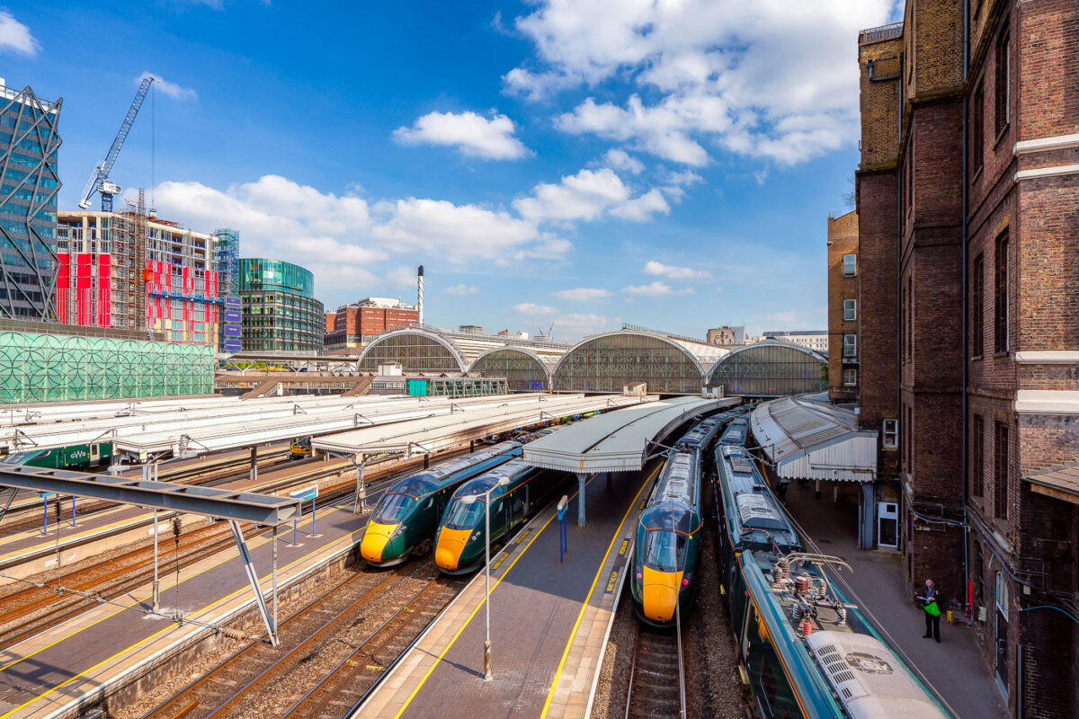 Modern high-speed trains wait beneath the soaring glass arches of Paddington Station in London, one of the capital’s busiest rail hubs. Designed in the mid-19th century by engineer Isambard Kingdom Brunel, the station blends historic architecture with the bustle of contemporary travel, serving as the terminus for Great Western Railway routes to Wales and the West Country. Around the concourse, new developments and construction highlight the area’s transformation, with Paddington’s mix of heritage and modernity on full display.
