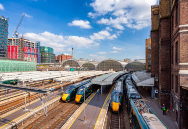 Modern high-speed trains wait beneath the soaring glass arches of Paddington Station in London, one of the capital’s busiest rail hubs. Designed in the mid-19th century by engineer Isambard Kingdom Brunel, the station blends historic architecture with the bustle of contemporary travel, serving as the terminus for Great Western Railway routes to Wales and the West Country. Around the concourse, new developments and construction highlight the area’s transformation, with Paddington’s mix of heritage and modernity on full display.