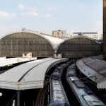 Paddington Station Trains Beneath the Historic Arched Roofs 3 The trains at Paddington Station sit beneath the grand arched glass-and-iron roofs first designed by Isambard Kingdom Brunel and Matthew Digby Wyatt in the 1850s. The repeating barrel-vaulted structures—still marked by the faded “GWR” insignia for the Great Western Railway—remain a hallmark of Victorian railway engineering. Now serving modern intercity services such as the GWR and Heathrow Express, the station continues to blend historic design with contemporary rail operations, standing as one of London’s most architecturally significant transport hubs.