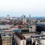 Captured from one of the observation capsules of the London Eye, this elevated southwest-facing view looks across the South Bank and Waterloo Station toward the district of Vauxhall and the emerging skyline of Nine Elms and Battersea. The large curved glass roofs of Waterloo Station dominate the foreground, marking one of London’s busiest rail terminals. Beyond it, a mix of modern residential towers—including St George’s Wharf Tower and various recent high-rise developments—signal the transformation of South London’s riverfront. The image illustrates the urban evolution from historic masonry buildings near the Thames to new commercial and residential architecture further out, highlighting London’s shifting development landscape.