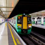 A Southern Railway Class 377 electric multiple unit pauses at one of the below-ground platforms of London Victoria, one of the busiest rail termini in the United Kingdom. Victoria Station serves as a major gateway for commuters and regional travelers across southern England, hosting both suburban services and longer-distance connections toward Sussex, Surrey, and the south coast. The station, originally opened in 1860, has undergone numerous renovations to accommodate modern passenger capacity, yet retains its functional layout with wide concourses, numbered platforms, overhead signage, and the familiar “Mind the Gap” platform warning. The photo highlights the integration of historic rail infrastructure with contemporary rolling stock, reflecting the continuing importance of national rail in London’s transit network.
