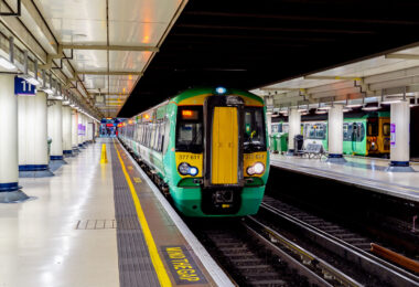 A Southern Railway Class 377 electric multiple unit pauses at one of the below-ground platforms of London Victoria, one of the busiest rail termini in the United Kingdom. Victoria Station serves as a major gateway for commuters and regional travelers across southern England, hosting both suburban services and longer-distance connections toward Sussex, Surrey, and the south coast. The station, originally opened in 1860, has undergone numerous renovations to accommodate modern passenger capacity, yet retains its functional layout with wide concourses, numbered platforms, overhead signage, and the familiar “Mind the Gap” platform warning. The photo highlights the integration of historic rail infrastructure with contemporary rolling stock, reflecting the continuing importance of national rail in London’s transit network.