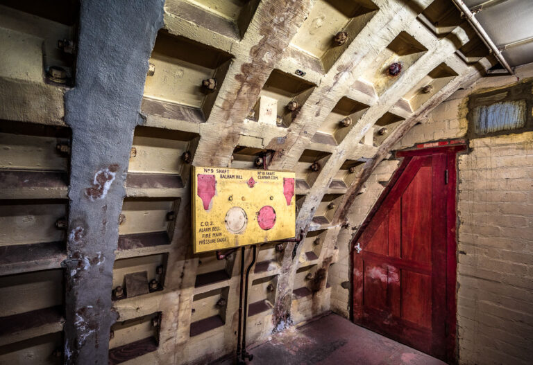 Clapham South Shelter: WWII Pressure Control Panel 3 This pressure control and alarm panel is a remnant of the Clapham South deep-level shelter, a crucial component of London's World War II civil defense infrastructure. Constructed 36 meters underground and completed in 1942, the shelter was designed to protect up to 8,000 civilians from air raids. The panel, marked for Shafts 9 and 10, monitored vital life-support systems including air pressure, fire mains, and CO₂ levels. Its robust steel and cast-iron construction, along with visible signs of wartime paint, underscore the industrial engineering and resilience that characterized London's wartime survival efforts.