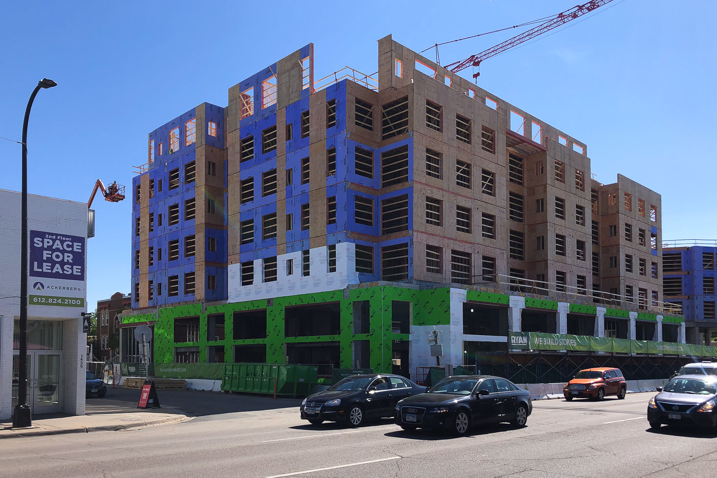 Daymark Apartments under construction in Uptown Minneapolis with a crane, lift, and traffic in front.