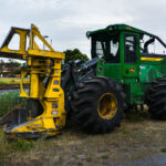 A John Deere 843L feller buncher sits parked near the railway tracks in St. Louis Park, Minnesota, during the early stages of construction for the Southwest Light Rail Transit (LRT) project. Designed primarily for forestry work, this heavy-duty machine—with its massive front grapple and thick treaded tires—was adapted for clearing brush and trees along the rail corridor. The mix of heavy equipment, rail infrastructure, and suburban backdrop highlights the region’s ongoing transformation as the light rail expansion reshapes Minneapolis’s western suburbs.