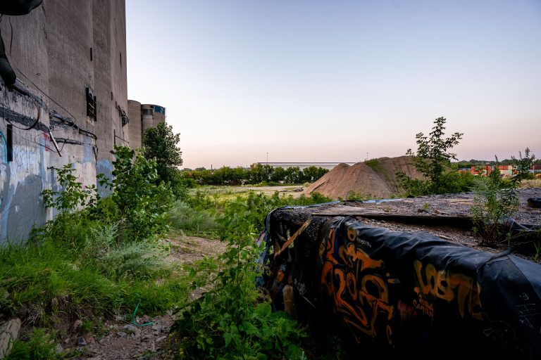 Overgrown Lot Beside ADM Grain Elevator, Minneapolis 3 Overgrown lot with graffiti-covered container beside concrete grain silos at the former ADM elevator in Minneapolis