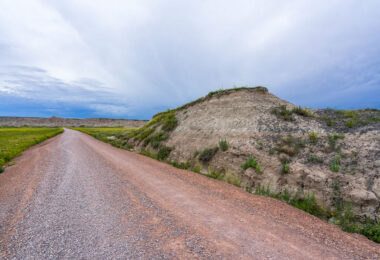 A weathered wooden sign marks the rugged entrance to Sheep Mountain in the southern reaches of Badlands National Park, South Dakota. This remote area, surrounded by the sweeping prairies of Buffalo Gap National Grassland, offers one of the park’s most dramatic and less-visited overlooks. The region sits within Oglala Lakota lands, where erosion has sculpted colorful buttes and steep ridges over millions of years. Accessible by an unpaved road, Sheep Mountain remains a quiet, untamed corner of the Badlands, revealing the deep geologic and cultural layers of the Northern Plains.
