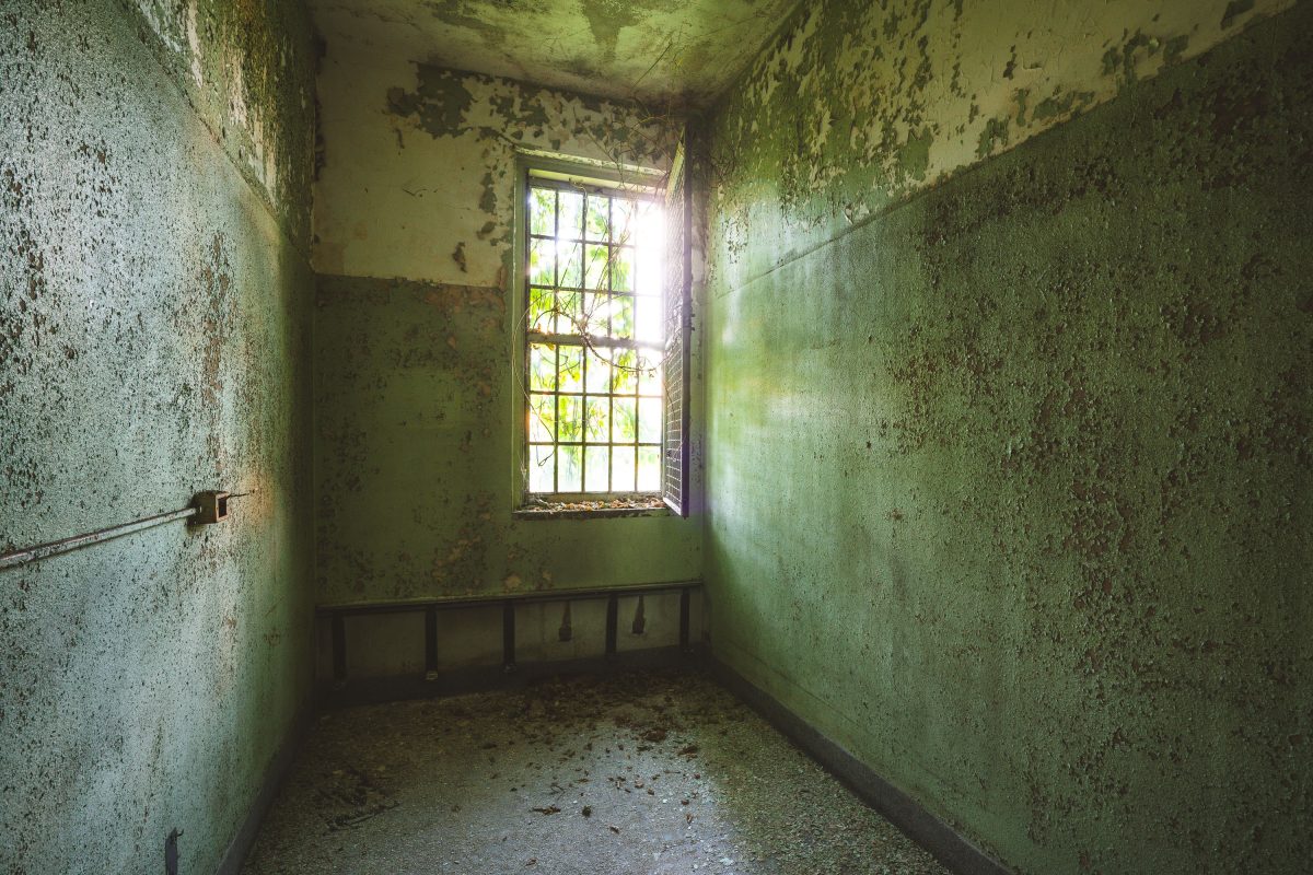 Deteriorated hospital room with barred window at abandoned Creedmore Psychiatric Center, New York.