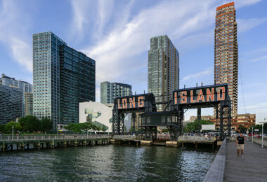 The iconic Long Island sign towers over the East River waterfront in Queens as evening light reflects off the glassy high-rises of Long Island City. Once a gritty industrial dock, the area has transformed into one of New York City’s fastest-growing neighborhoods.
