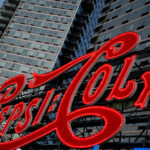 The iconic Pepsi-Cola sign glows in red neon along the East River waterfront in Long Island City, Queens. The landmark sign, originally installed in 1936, now stands in front of modern residential towers and remains a prominent feature of the New York City skyline.
