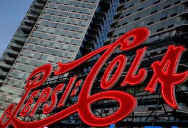 The iconic Pepsi-Cola sign glows in red neon along the East River waterfront in Long Island City, Queens. The landmark sign, originally installed in 1936, now stands in front of modern residential towers and remains a prominent feature of the New York City skyline.