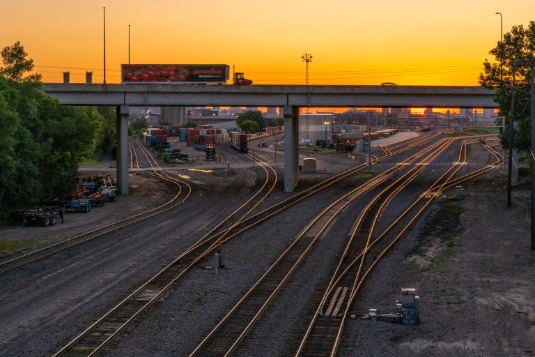 Truck Crossing Highway 280 Over the Rail Yard at Sunset 1 Rail yard with illuminated tracks beneath a highway overpass at sunset in Minneapolis, Minnesota.