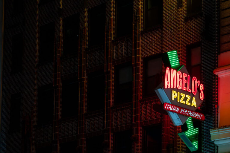 Angelo's Pizza in Manhattan 3 A neon sign for Angelo’s Pizza glows against the brick facade of a building in Midtown Manhattan. The Italian restaurant, located near the Ed Sullivan Theater, adds to the neighborhood’s mix of nightlife and dining spots illuminated after dark.