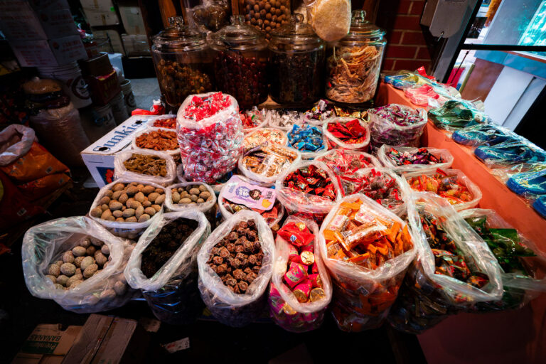 Chinatown NYC Market: Dried Fruits, Candies, and Snacks 2 A market stall in New York's Chinatown displays a variety of dried fruits, candies, and snacks in plastic bags and glass jars.