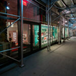 Sidewalk on Madison Avenue showing a row of storefronts under scaffolding late at night on Madison Avenue in Manhattan. The Christian Louboutin store window.