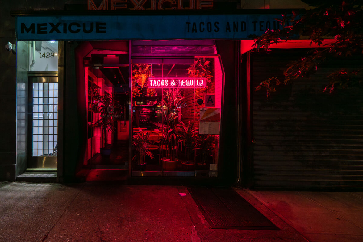 The neon sign for Mexicue restaurant, advertising Tacos & Tequila, is illuminated at 1429 Lexington Avenue in New York City.