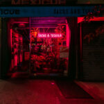 A red neon sign reading “Tacos & Tequila” glows in the window of Mexicue, a restaurant on Lexington Avenue in Manhattan.