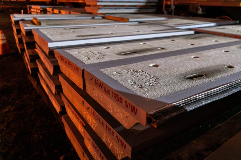 Stacked concrete railroad crossing panels with metal reinforcement stored outdoors in Minneapolis.