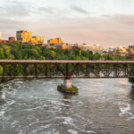 Bridges linking the University of Minnesota East and West banks in Minneapolis. Evening light reflects off campus buildings, including the Weisman Art Museum and the Phillips-Wangensteen Building.