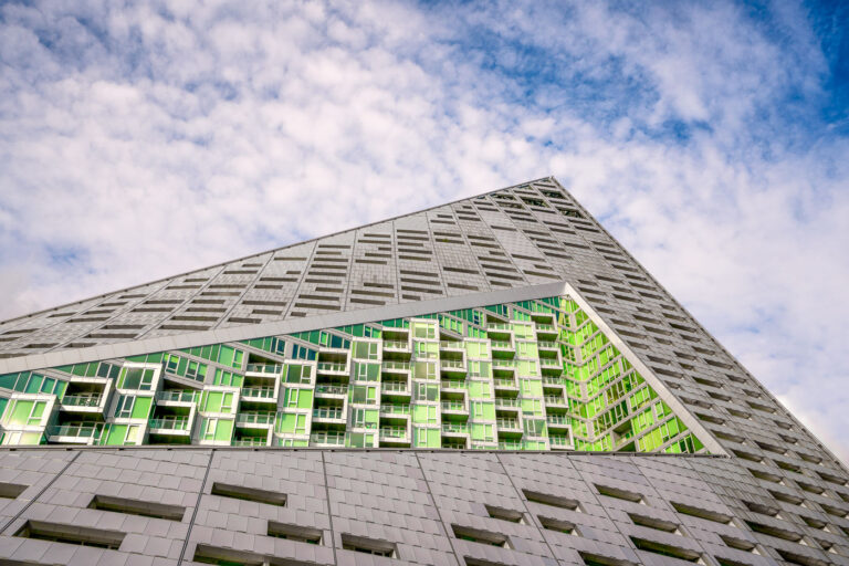 VIA 57 West Residential Building, New York City 1 The VIA 57 West residential building in New York City, designed by Bjarke Ingels Group, features a distinctive pyramidal form with a grey facade and green-tinted glass balconies.