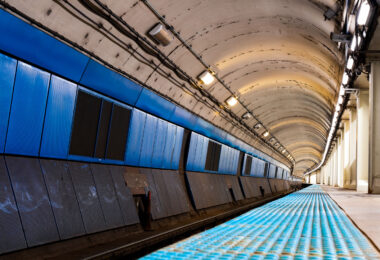 The curved platform of a Chicago Transit Authority Blue Line station reveals the utilitarian design of the city’s subway infrastructure, part of the Milwaukee–Dearborn subway opened in 1951. The tunnel’s tiled blue panels and low arched ceiling reflect the postwar engineering era that brought rapid transit beneath the Loop and the West Side, connecting O’Hare International Airport to downtown. Despite its age, this corridor remains a vital artery in Chicago’s daily commuter network, a symbol of mid-century urban mobility still in constant motion beneath the city streets.