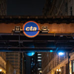 The Chicago Transit Authority (CTA) logo is displayed beneath the steel elevated tracks that define the Loop, the city’s central business district. The structure, part of the “L” system first built in the late 19th century, remains one of Chicago’s most enduring symbols of urban mobility. Overhead girders and riveted beams—many still original to the early 1900s—carry trains above streets lined with early skyscrapers and historic facades. The CTA continues to operate one of the largest and oldest public transit networks in the United States, moving more than a million riders daily through Chicago’s interconnected system of rail and bus lines.
