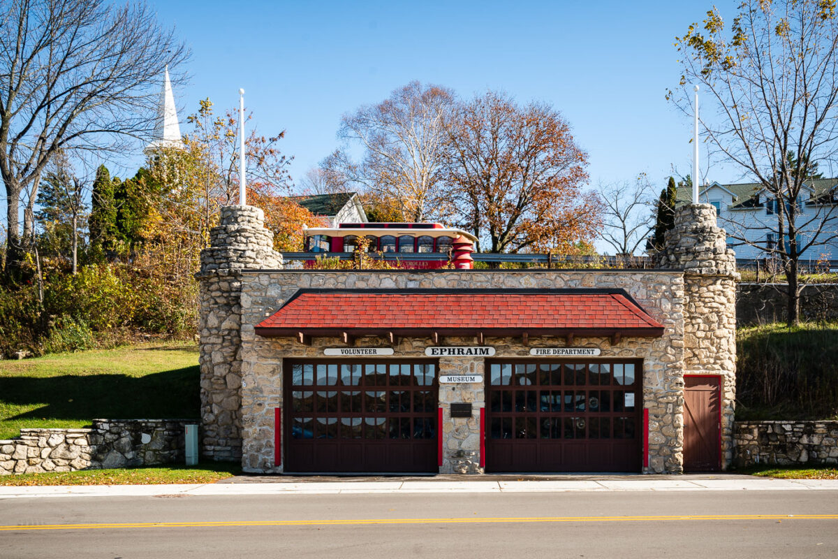 The historic Ephraim Volunteer Fire Department Museum, housed in a stone building with classic red doors, stands as a reminder of small-town service and heritage in Ephraim, Wisconsin.