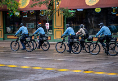 Police on bicycles patrol downtown Minneapolis outside the Target Center while protesters and rally-goers gather ahead of a 2019 Trump campaign event.