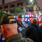 During demonstrations outside President Donald Trump’s campaign rally at the Target Center in downtown Minneapolis on October 10, 2019, a man wearing a hat bearing the Oath Keepers insignia asked for directions near the crowd. The rally drew both Trump supporters and counter-protesters, filling Hennepin Avenue with thousands of people and heavy police presence. The Oath Keepers, founded in 2009, is a far-right, anti-government militia organization whose members have been linked to armed protests and later to the January 6, 2021, U.S. Capitol attack.