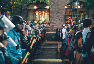 Minneapolis police officers in riot gear form a barricade opposite protesters outside the Target Center on October 10, 2019, during then-President Donald Trump’s campaign rally. The tightly organized police line extended along First Avenue, separating demonstrators from event attendees as tensions rose late into the evening. The rally drew thousands of protesters and supporters to downtown Minneapolis, prompting one of the largest coordinated law enforcement deployments in the city that year.