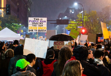 Protesters fill the intersection near the Target Center in downtown Minneapolis during Donald Trump’s campaign rally on October 10, 2019. Demonstrators carried homemade signs, including one reading “This is Purple Rain Country—Take Your Golden Showers Back to Russia,” referencing Minnesota’s musical icon Prince and the controversies surrounding Trump’s presidency. The rally drew thousands of protesters and supporters alike, marking one of the city’s largest political demonstrations since the 2016 election.