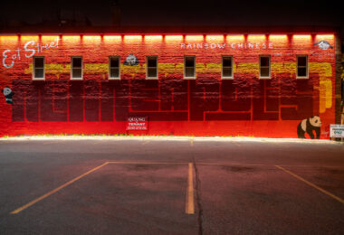 The bright red mural on the side of Rainbow Chinese Restaurant at 2739 Nicollet Avenue anchors Minneapolis’s iconic “Eat Street” corridor. Painted in bold geometric letters spelling “Minneapolis,” the work was designed to celebrate the neighborhood’s cultural diversity and long history as a hub for immigrant-owned restaurants. The panda motif and stylized lettering nod to the restaurant’s founder, Tammy Wong, whose establishment has been a local fixture since 1987. The mural, illuminated at night by warm overhead lighting, has become a recognizable landmark symbolizing the creative and culinary energy of Eat Street in the Whittier neighborhood.