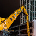 A Royal Taylor demolition excavator works overnight in downtown Chicago, dismantling the remains of a mid-century parking structure near North Wabash Avenue. The location, part of an area undergoing major redevelopment, reflects the city’s continual cycle of teardown and renewal. Once a dense cluster of low-rise commercial and industrial buildings, this district is being transformed by modern high-rise towers and mixed-use developments that are reshaping the skyline and urban streetscape of central Chicago.