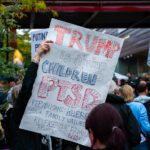 A protester holds up protest sign outside the Target Center in Downtown Minneapolis where Trump was to speak in October 2019.