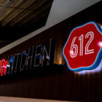 An illuminated “612 Burger Kitchen” sign inside U.S. Bank Stadium in Minneapolis, named after the city’s area code. The bold red-and-black typography and retro badge design reflect a blend of local identity and modern stadium branding. Located among the venue’s food and beverage concessions, 612 Burger Kitchen is part of the stadium’s effort to feature Minneapolis-based culinary offerings for fans attending Minnesota Vikings games and large-scale events.