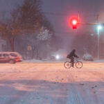 Cyclist on Lyndale Avenue During 2019 Snowstorm 1 A cyclist crosses Lyndale Avenue South during the heavy November 26, 2019 snowstorm in Minneapolis. Despite low visibility and slick streets, a few commuters still braved the conditions, illuminated by red traffic lights and snow-diffused streetlamps. The image captures the perseverance of winter cycling culture in the Twin Cities, where even severe weather rarely stops movement through the urban grid.