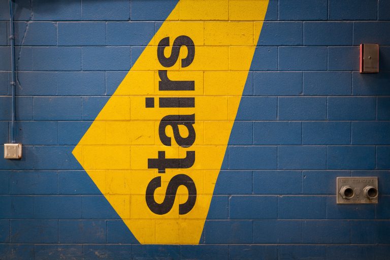 Stairs Sign, Parking Garage in Downtown Minneapolis 1 Yellow arrow with the word "Stairs" painted on a blue cinder block wall in a Minneapolis parking garage.