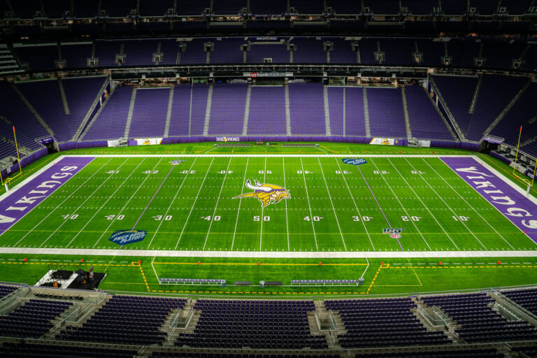U.S. Bank Stadium Field, Home of the Minnesota Vikings 2 The interior of U.S. Bank Stadium in Minneapolis, home of the NFL’s Minnesota Vikings, shown from a high vantage point with an unobstructed view of the field. Completed in 2016 on the former site of the Metrodome, the $1.1 billion stadium features a fixed, translucent ETFE roof and steeply angled seating designed to evoke Nordic longhouses. The field displays the Vikings’ horned helmet logo at midfield, surrounded by vibrant purple end zones and the signature “SKOL” rally cry—a modern landmark of downtown Minneapolis and a hub for major sporting and entertainment events.