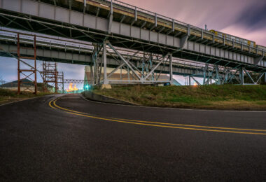 On Baton Rouge’s Airline Highway, the road snakes beneath a tangle of overpasses and steel supports, a striking symbol of mid-20th-century infrastructure. Originally developed as a major bypass route, Airline Highway became one of Louisiana’s busiest commercial arteries, linking petrochemical plants, warehouses, and neighborhoods across the capital region. At dusk, the glow of distant lights cuts through the industrial sprawl, underscoring how this corridor remains a vital — if gritty — backbone of the city’s economy and daily life.