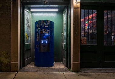 A blue ATM sits in a narrow doorway at 211 Decatur Street in New Orleans, surrounded by graffiti and stickers. T