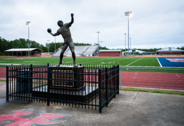 In Kiln, Mississippi, the legacy of Brett Favre looms large. Outside Hancock High School’s football stadium, a life-sized statue of the quarterback stands mid-throw, immortalizing the local athlete who went on to become one of the NFL’s most prolific passers. Set against the backdrop of the school’s red track and green turf, the monument reflects both community pride and the enduring place of football in Southern culture. For locals, it serves as a reminder that even from a small Gulf Coast town, greatness can reach the national stage.