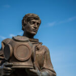 The Sponge Diver Memorial in Tarpon Springs, Florida, honors the Greek immigrants who established the town’s sponge diving industry in the early 1900s. The bronze statue depicts a diver holding a traditional brass helmet, symbolizing the skill and danger of the underwater trade. Located near the historic Sponge Docks, it serves as a tribute to the workers who helped shape the community’s maritime heritage.
