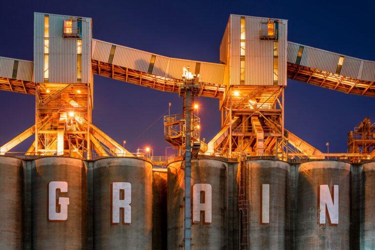Grain Silos at Zen-Noh Grain Terminal, Convent LA 1 Illuminated under floodlights, the massive concrete grain silos of the Zen-Noh Grain Corporation terminal rise over the Mississippi River in Convent, Louisiana. Operated by a U.S. subsidiary of Japan’s Zen-Noh agricultural cooperative, this export facility plays a critical role in shipping Midwestern grain to international markets. The illuminated conveyors and loading structures highlight the region’s industrial link between river transport and global food supply chains.