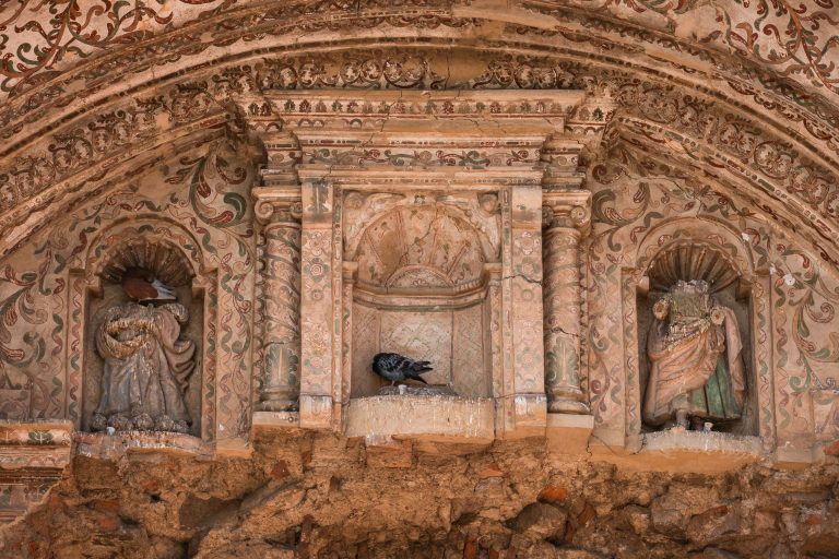Saint Statues in Ornate Niches, Colonial Church Facade 3 Ornate carved stone archway with decorative sculptures and relief carvings in terracotta tones.