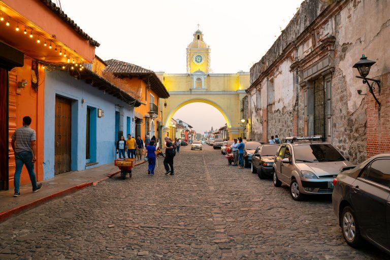 Santa Catalina Arch at Sunset, Antigua Guatemala 1 Colorful colonial street in Antigua, Guatemala, with yellow church archway and parked cars.