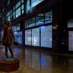 The iconic bronze statue of Mary Tyler Moore along Nicollet Mall in downtown Minneapolis, depicting the memorable hat-tossing moment from the opening of The Mary Tyler Moore Show, which first aired in 1970 and helped cement Minneapolis in television history. Installed in 2002, the statue symbolizes the city’s cultural association with the show’s themes of independence and optimism. At the time of this photograph, Nicollet Mall—normally a busy pedestrian and transit corridor—appears unusually empty, reflecting the early days of COVID-19 shutdowns that drastically reduced public presence in city centers. Blue public art lanterns, added during street improvements completed in 2017, line the renovated streetscape, emphasizing Nicollet Mall’s evolution as both a commercial and cultural landmark.