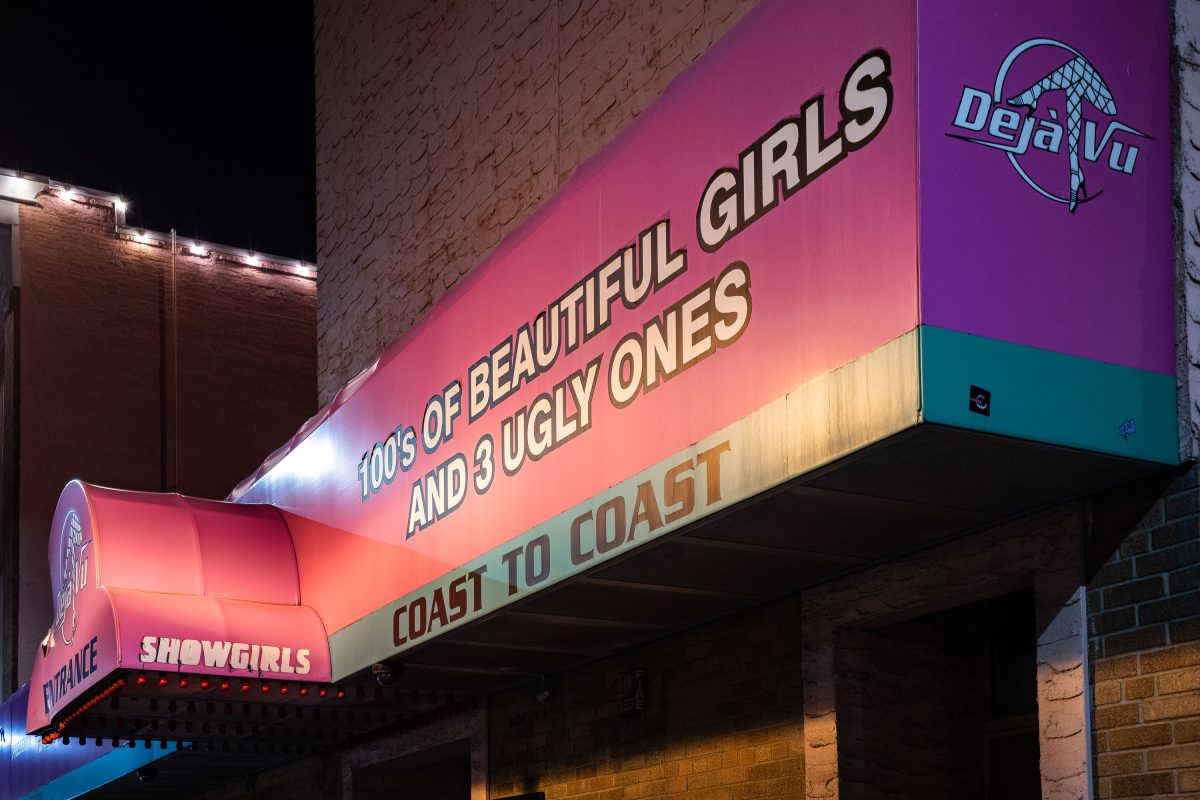 Neon sign for Deja Vu Showgirls strip club in Minneapolis displays humorous text about beautiful and ugly women.