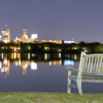 A bench at Bde Maka Ska in South Minneapolis. The Minneapolis skyline seen across the lake.